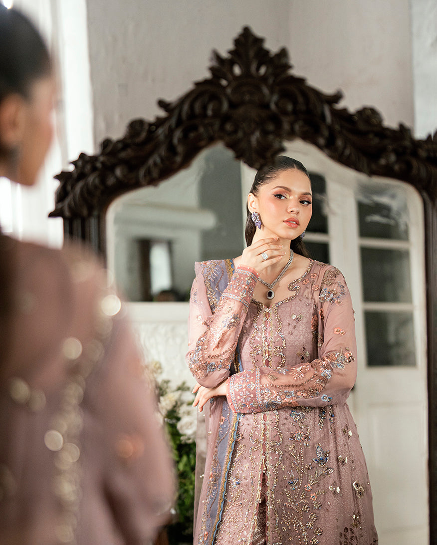 Reflection of the woman in an ornate mirror emphasizing the detailed embroidery and elegant styling of the ensemble
