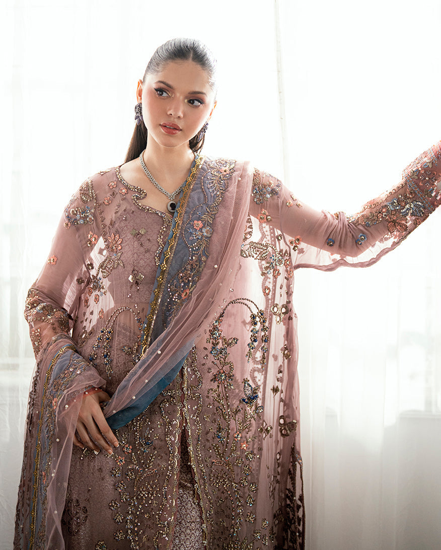 Woman modeling the outfit holding the sheer embroidered dupatta draped around her arm in soft natural lighting