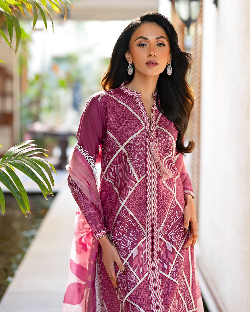 Close-up of woman wearing magenta embroidered lawn suit front, highlighting detailed geometric embroidery and tassel neckline with dangling earrings