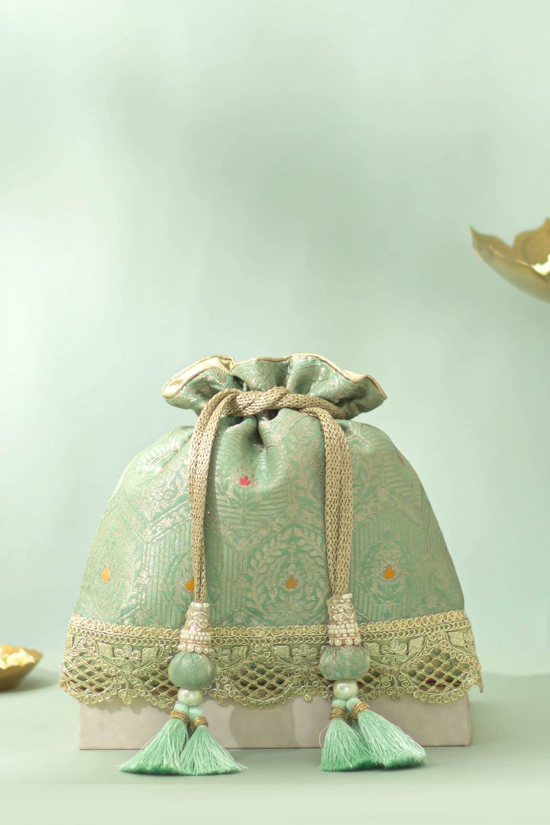 Pastel green silk potli bag with delicate gold embroidery, scalloped lace trim, braided drawstring, and decorative tassels