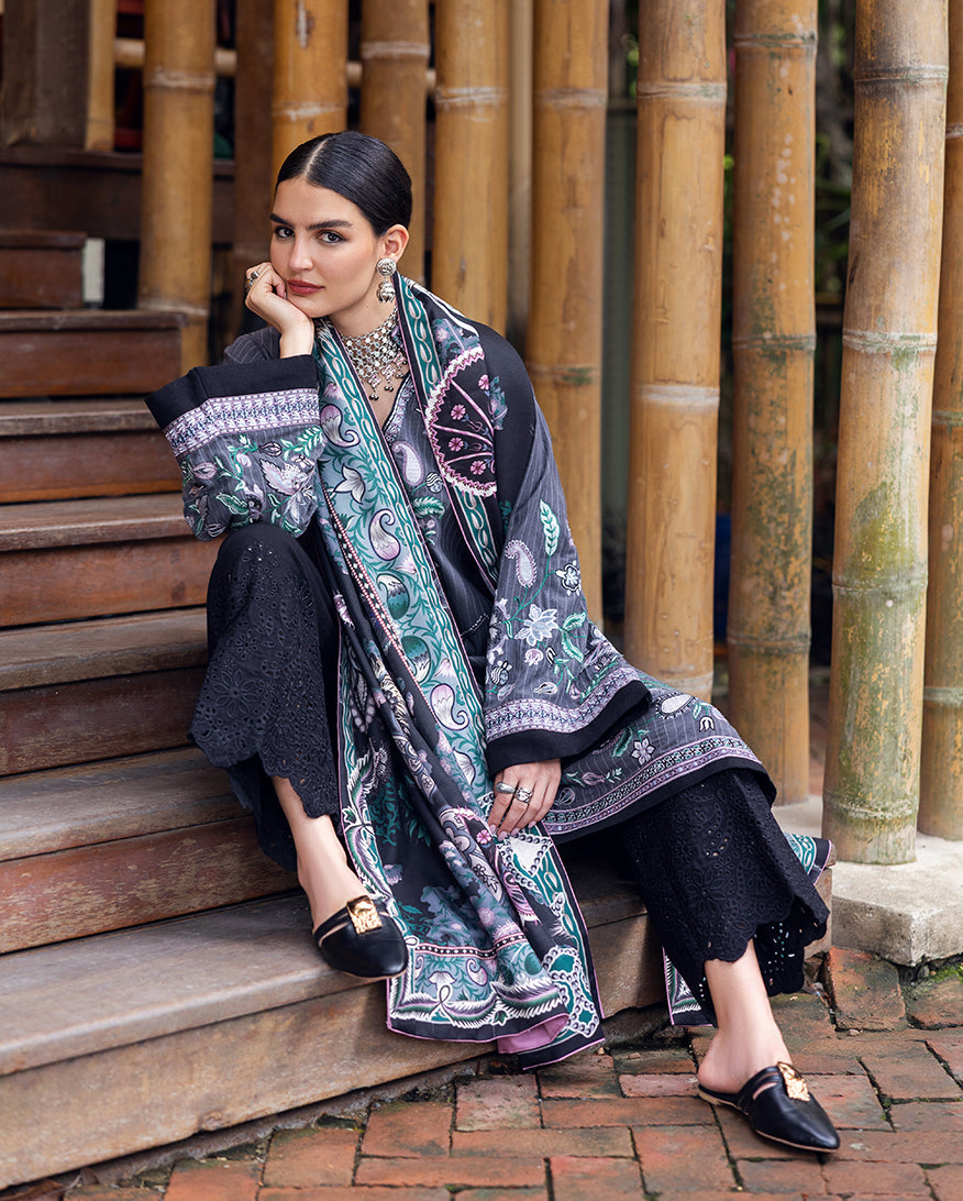 Seated woman displaying full embroidered Karandi outfit with shawl, showcasing floral embroidery and scalloped black trousers