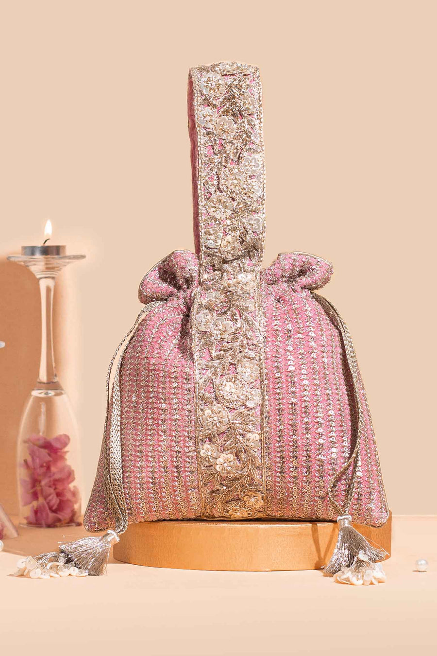 Luxurious pink potli bag with gold floral embroidery and tassel drawstrings, designed with an embroidered handle for festive occasions