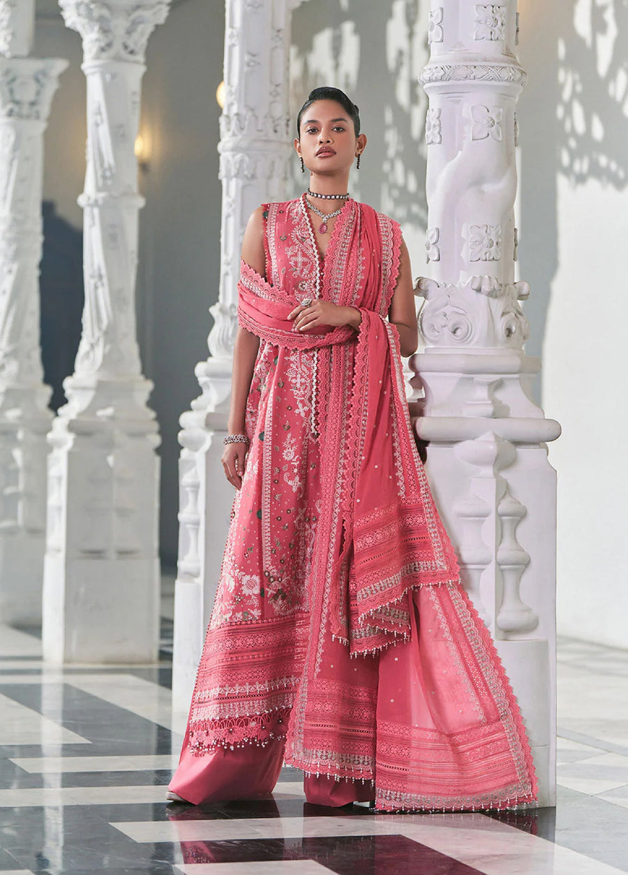 Woman wearing pink embroidered lawn suit with lace and bead-trimmed dupatta standing gracefully by decorated white pillars.