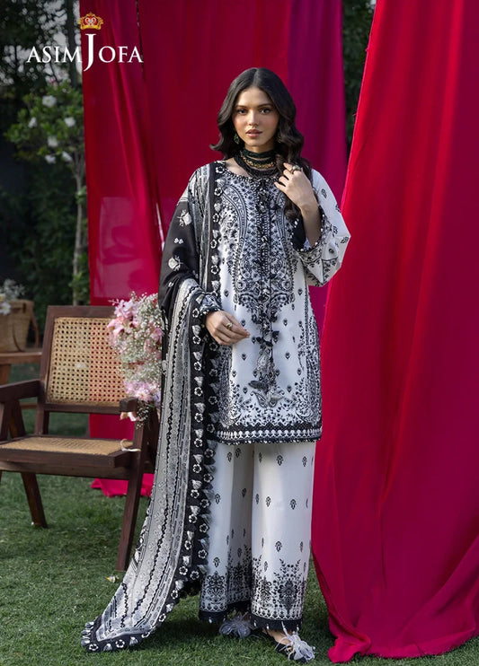 Woman wearing elegant black and white embroidered lawn suit with detailed floral and paisley embroidery, posing against a red backdrop.