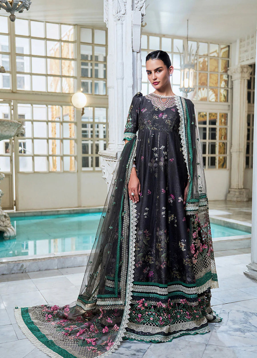 Front view of a woman wearing a black embroidered lawn suit with floral designs, lace trim, and a long flowing net dupatta with embroidery, standing indoors near a pool.