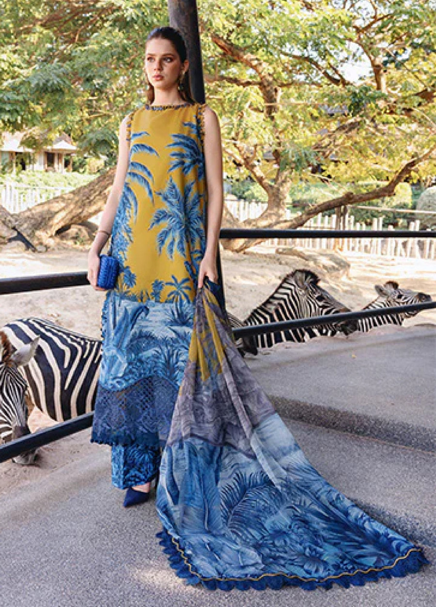 Woman wearing a sleeveless mustard yellow and blue printed lawn 3-piece suit standing outdoors near zebras