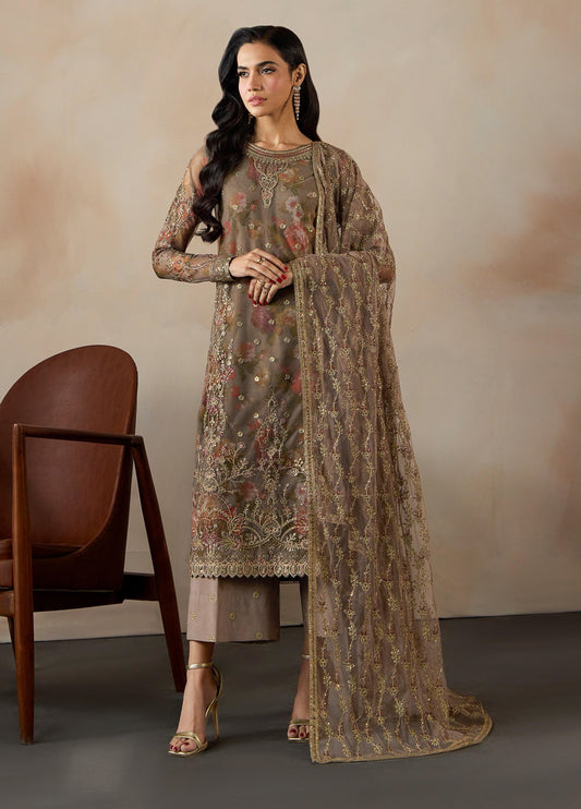 Woman standing in brown floral printed embroidered net 3-piece suit with matching dupatta and raw silk trousers, paired with golden heels