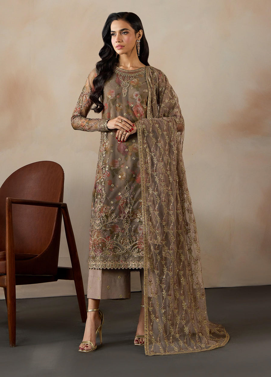 Woman standing in brown floral printed embroidered net 3-piece suit with matching dupatta and raw silk trousers, paired with golden heels