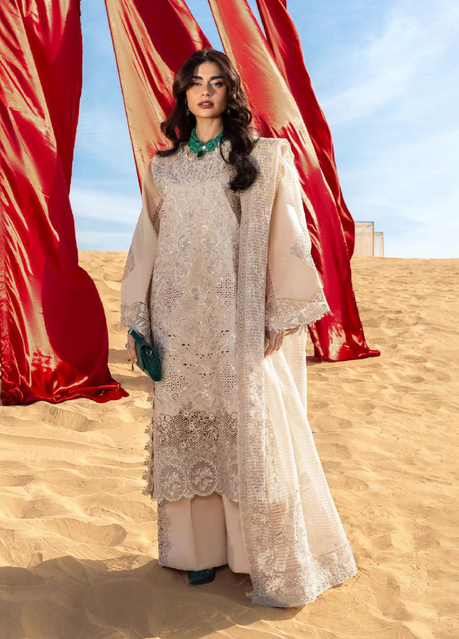 Woman standing on sand dunes wearing beige embroidered formal lawn suit with intricate floral embroidery and a matching dupatta under sunny sky