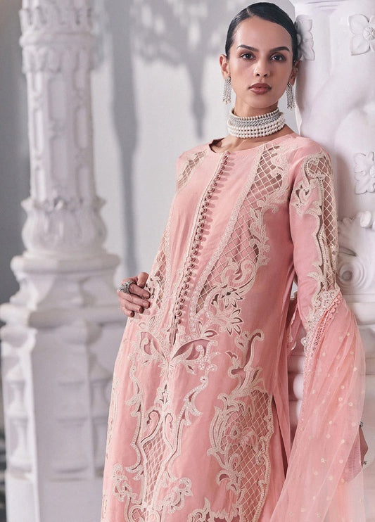 Close-up of model showcasing detailed embroidery and fabric-covered buttons on the front of the pink lawn suit, paired with pearl jewelry.