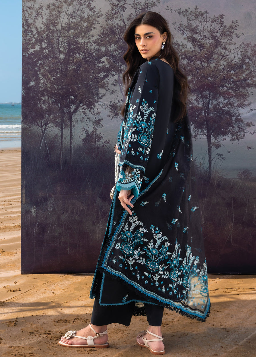 Side view of a woman in a black embroidered outfit showing detailed sleeve embroidery and sheer dupatta draped gracefully