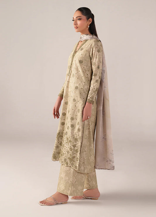 Side profile of woman modeling beige embroidered lawn suit with detailed floral embroidery on sleeves and front, showing chiffon dupatta draped over shoulder