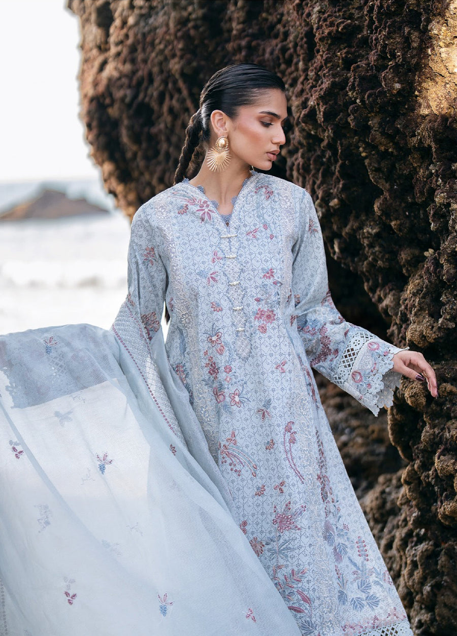 Close-up view of woman in embroidered lawn suit with detailed floral patterns and delicate lace cuffs, holding matching embroidered dupatta outdoors