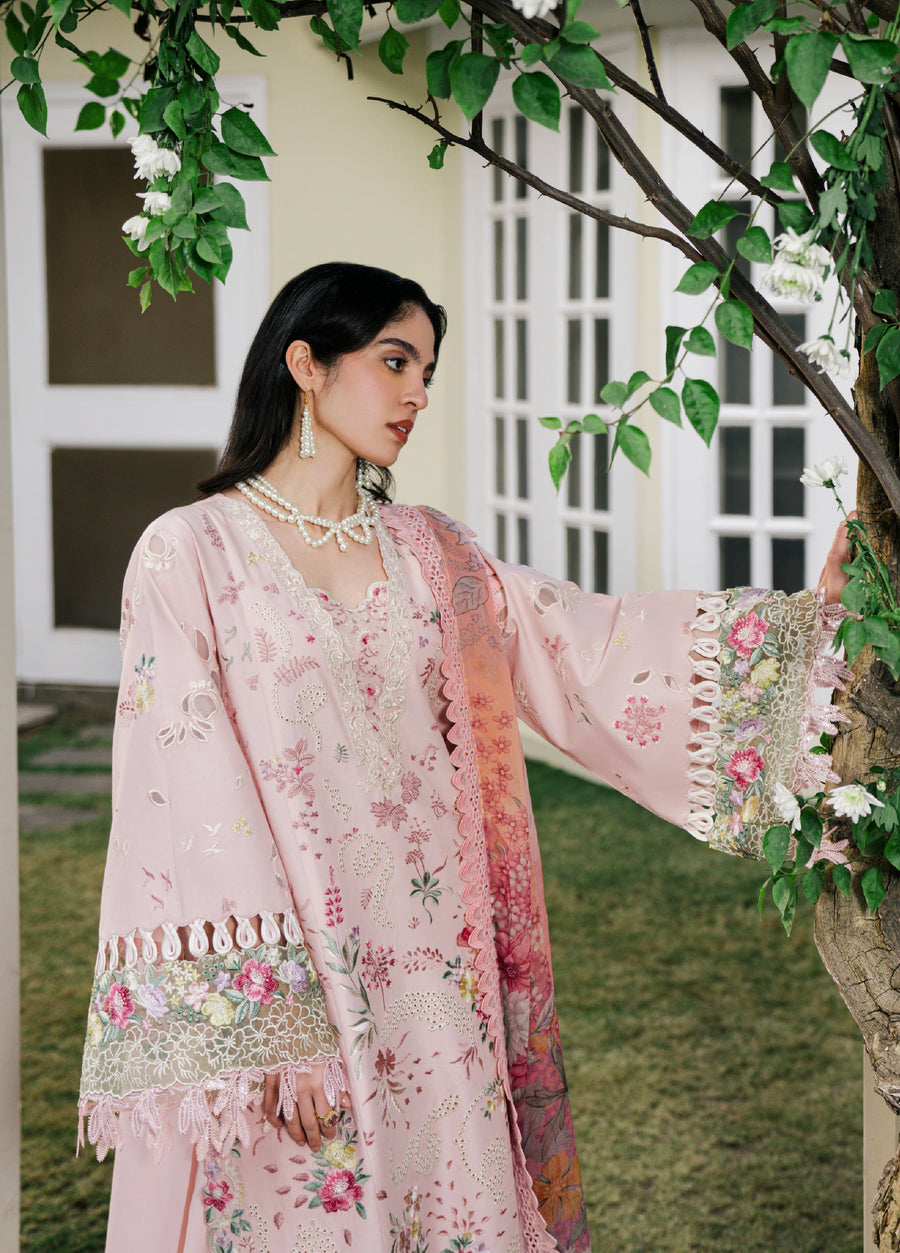 Woman posing outdoors in a baby pink floral embroidered lawn suit with intricate sleeve details and scalloped edges, touching a tree branch.