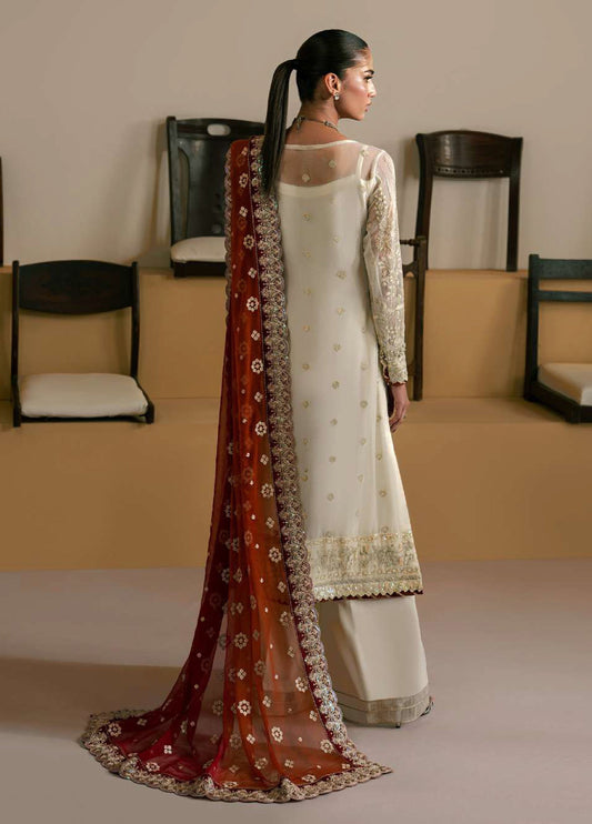 Back view of woman showcasing the delicate embroidery and mesh detail on ivory chiffon shirt with red-orange embroidered dupatta draped over shoulder