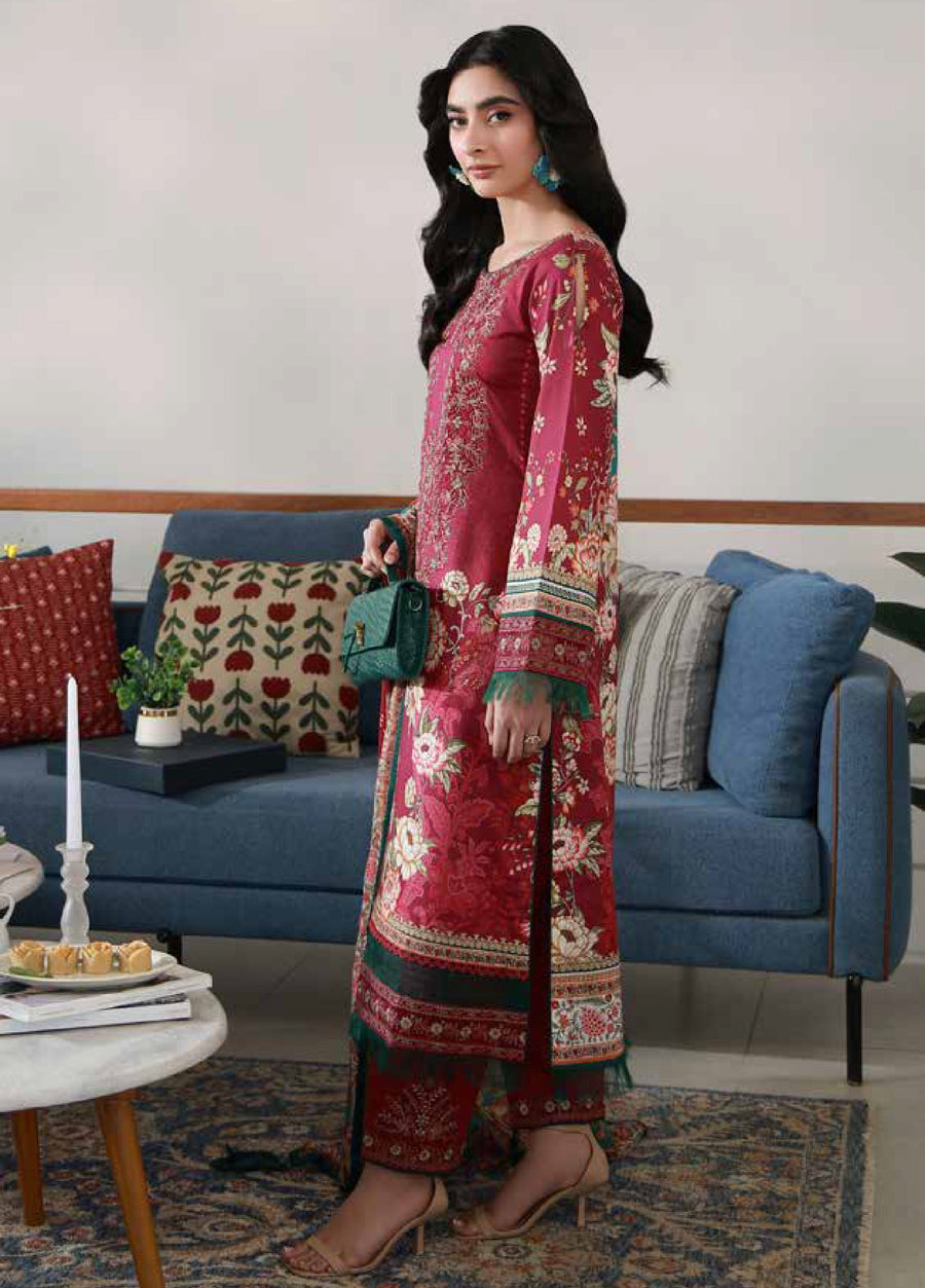 Side view of woman wearing embroidered red floral lawn suit with printed trousers and chiffon dupatta, revealing full sleeve embroidery and outfit length, accessorized with nude sandals and green earrings