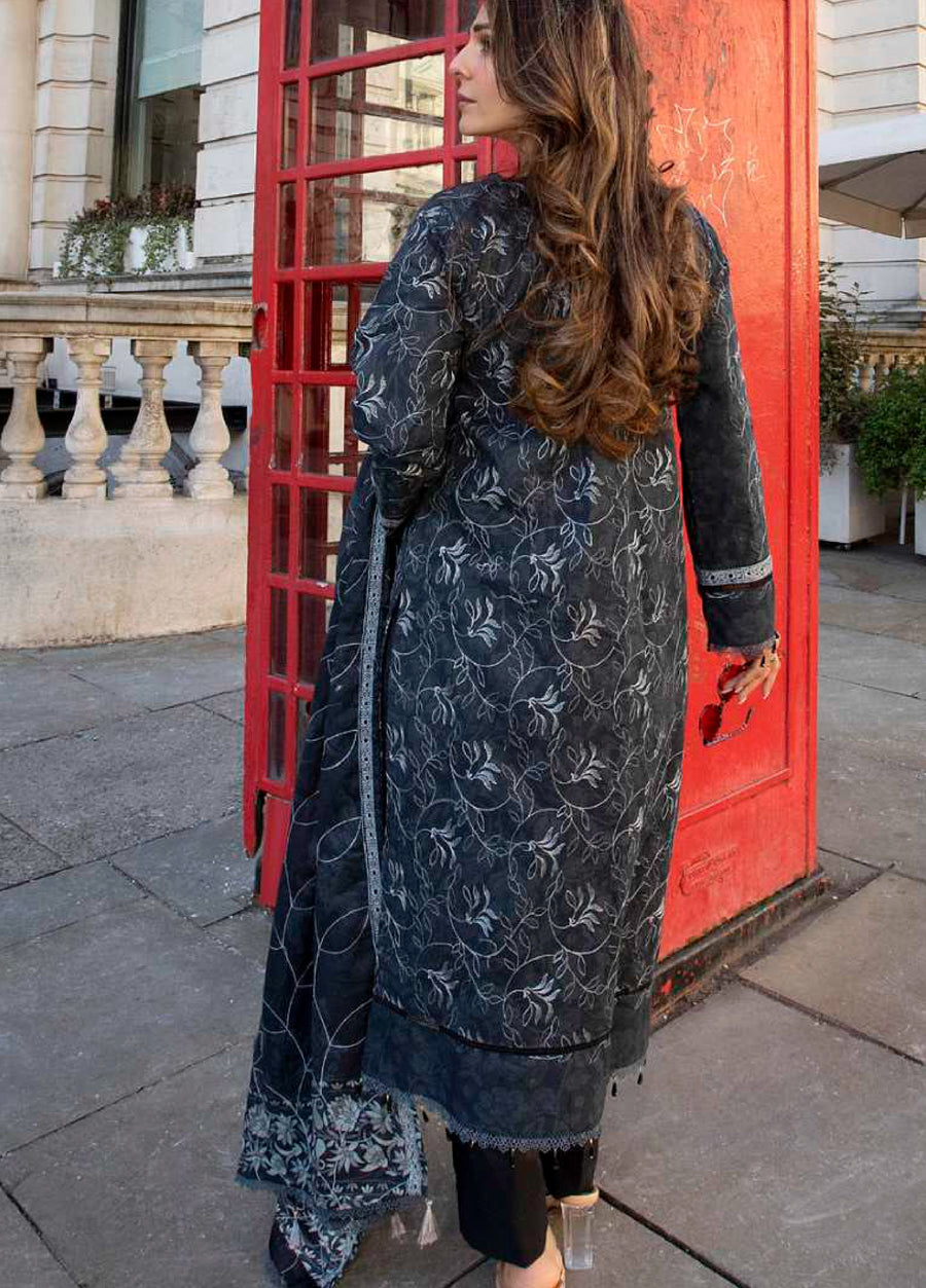 Back view of woman in embroidered lawn suit showing full floral embroidery and matching dupatta draped over shoulder against a red phone booth background
