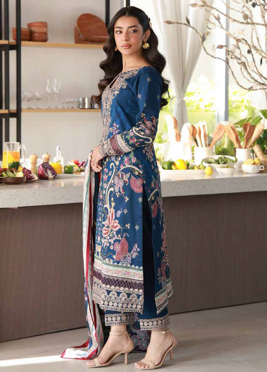 Side profile of a woman modeling the deep blue embroidered lawn shirt and slim trousers with detailed cuff embroidery, paired with an intricate printed dupatta
