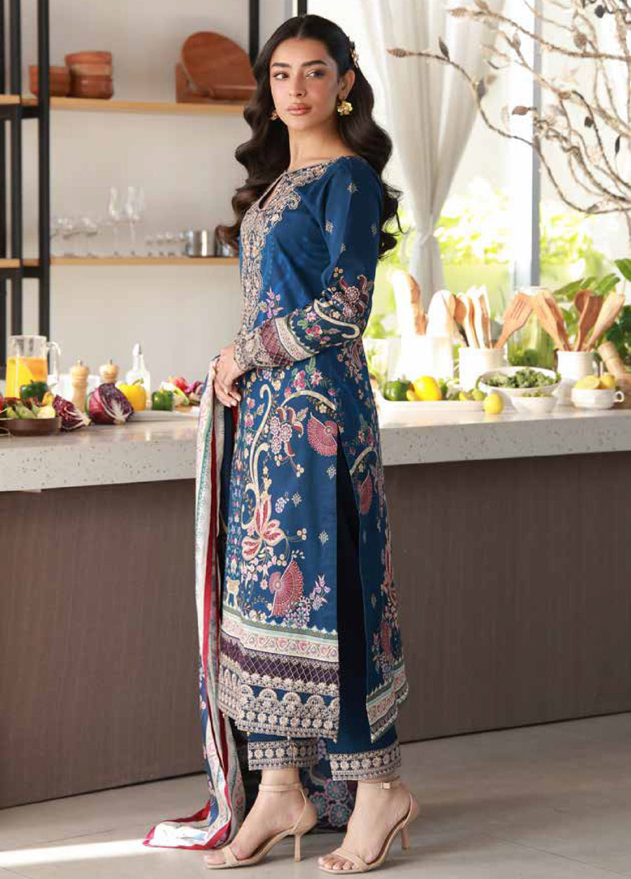 Side profile of a woman modeling the deep blue embroidered lawn shirt and slim trousers with detailed cuff embroidery, paired with an intricate printed dupatta