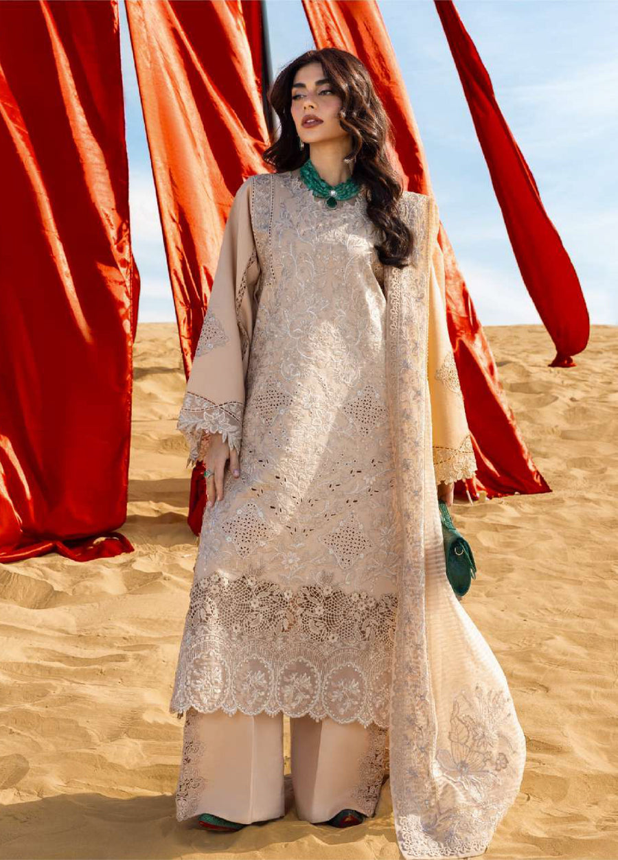 Full length side view of woman in beige embroidered suit with wide-leg trousers and detailed dupatta against red banners on sandy desert background