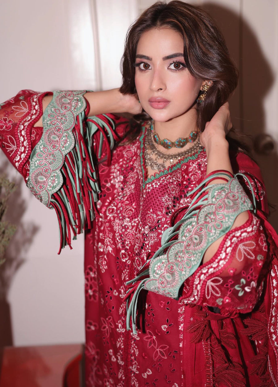 Close-up of woman showing intricate embroidery and green scalloped lace with fringes on the sleeves of the red suit