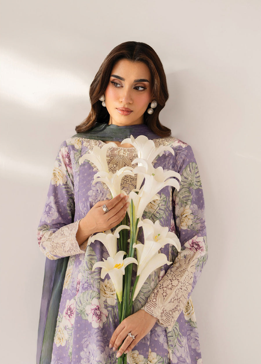 Close-up of a woman holding white lilies while wearing a lavender floral dress with detailed lace embroidery on the neckline and sleeves, accessorized with pearl earrings and rings.
