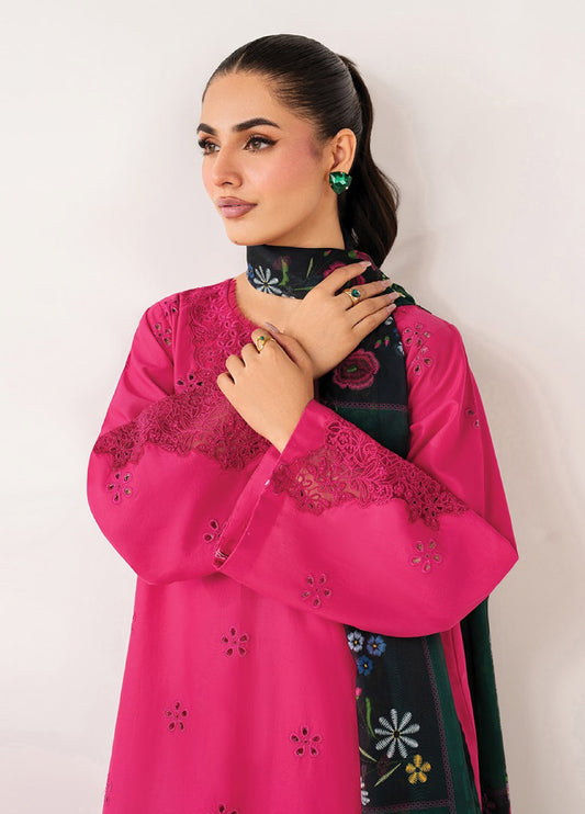 Close-up of woman in fuchsia lawn kurta showing detailed floral eyelet embroidery on sleeves and neckline, styled with matching green floral printed dupatta and green gemstone earrings