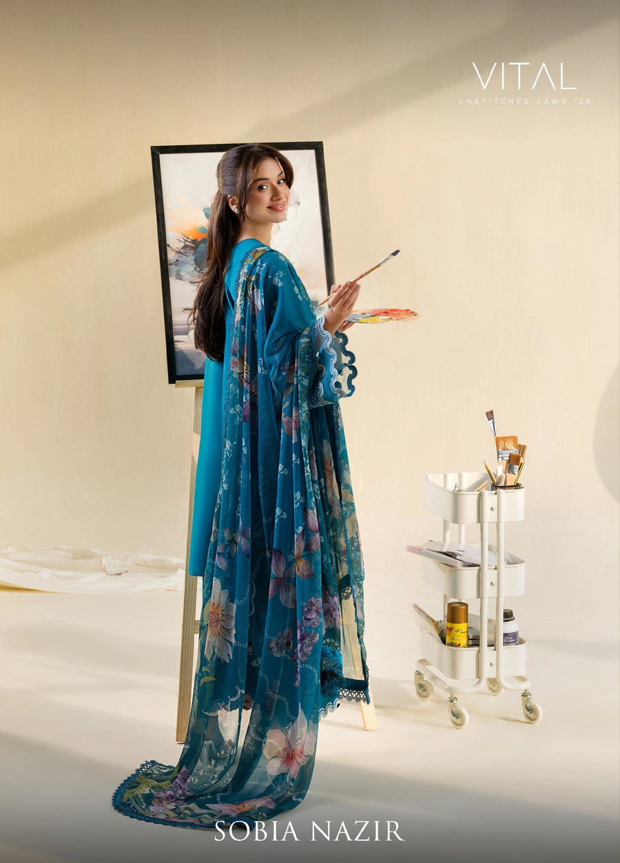 Side view of woman painting while wearing teal lawn suit with embroidered sleeves and flowing floral chiffon dupatta