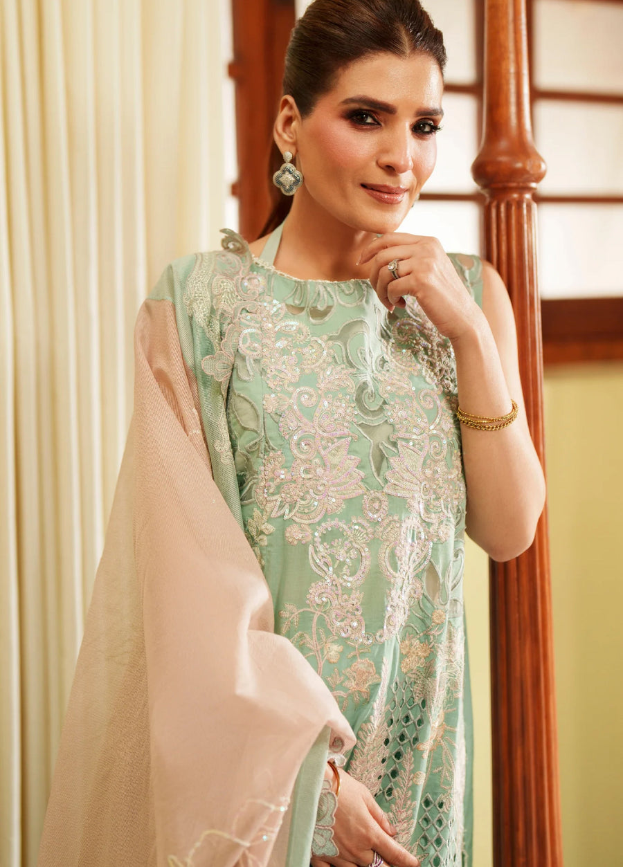 Close-up of a woman in a green embroidered sleeveless shirt with sequin accents, holding a beige shawl with delicate embroidery.