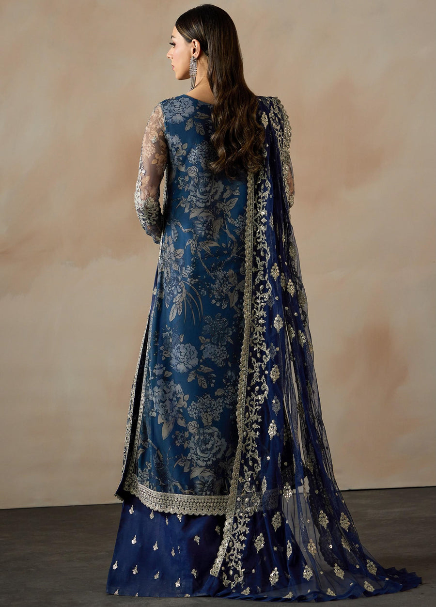 Rear view of a woman dressed in a navy blue embroidered net suit with floral patterns and an embellished net dupatta