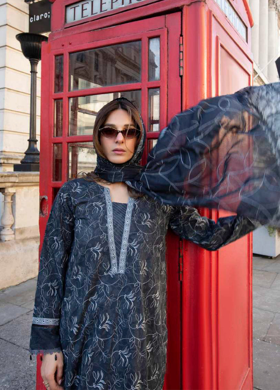 Woman posing with dupatta flying in the air wearing embroidered lawn suit, highlighting embroidered neckline and flowing fabric next to a red phone booth
