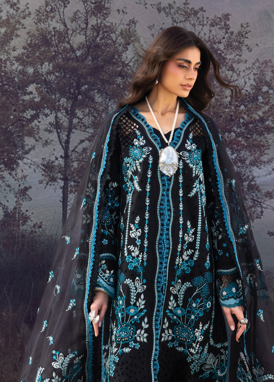 Close-up front view of model in black lawn suit with intricate blue and white embroidery, holding a pearl necklace