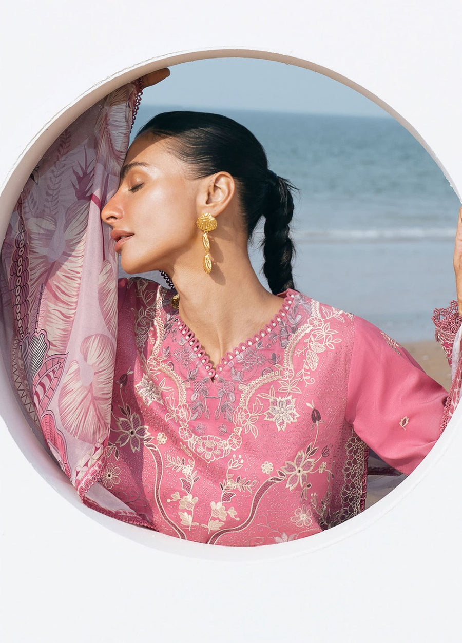 Close-up of woman in pink embroidered suit showing delicate floral embroidery on neckline and gold earrings