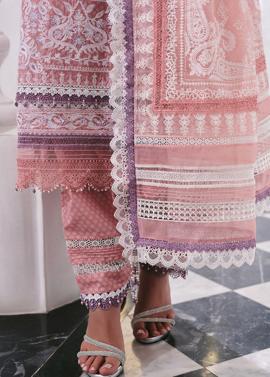 Detailed close-up of embroidered pink lawn suit fabric featuring lace edges and bead embellishments near silver open-toe heels