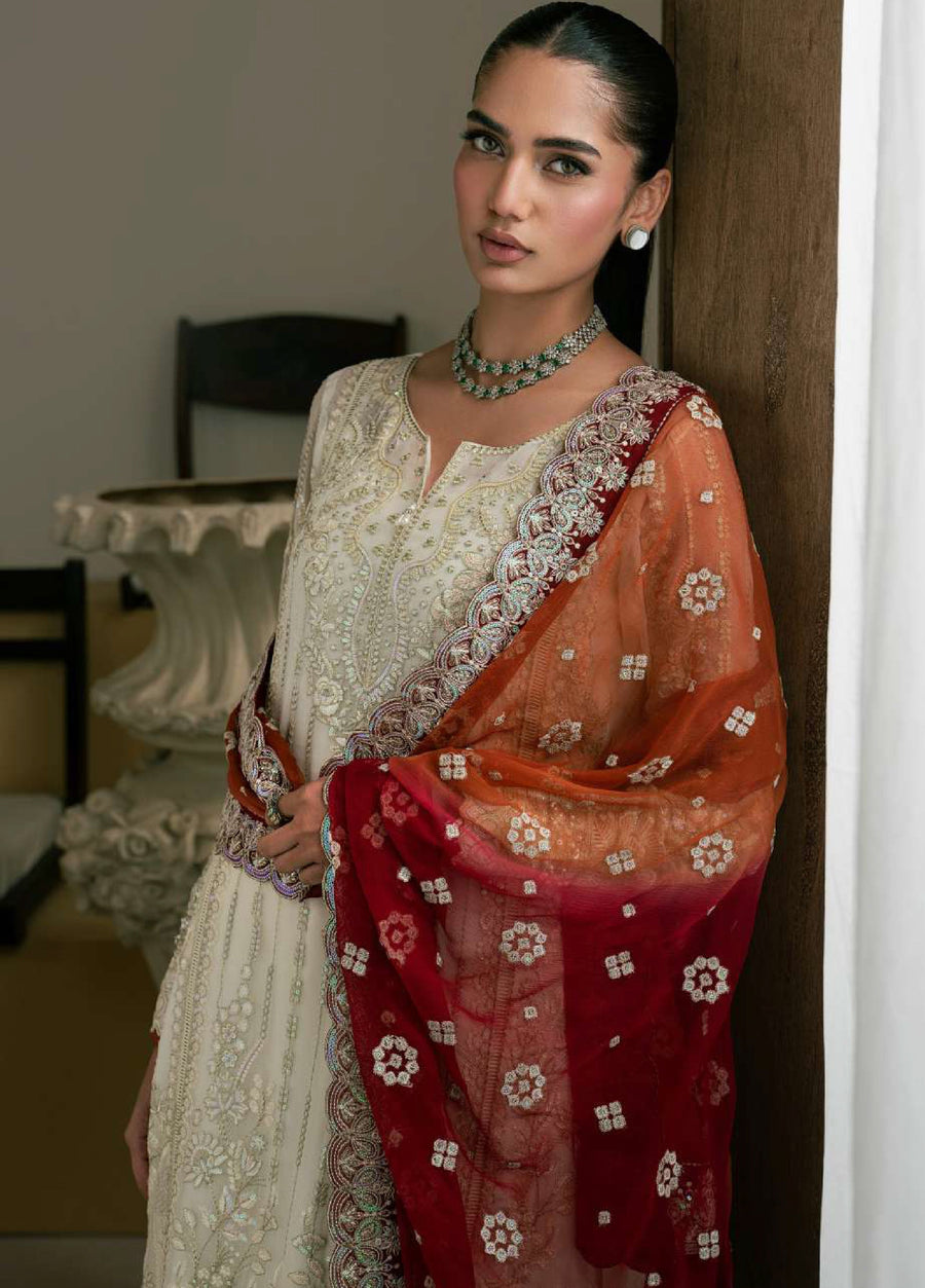 Close-up of woman with neatly styled hair wearing the embroidered chiffon shirt and holding the richly embroidered red-orange dupatta