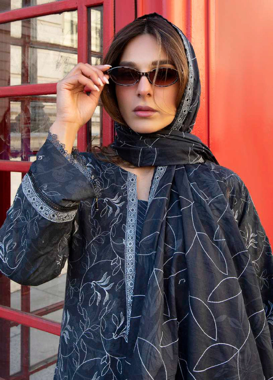 Close-up of woman adjusting sunglasses wearing embroidered lawn suit, showing detailed embroidery on sleeves and neckline