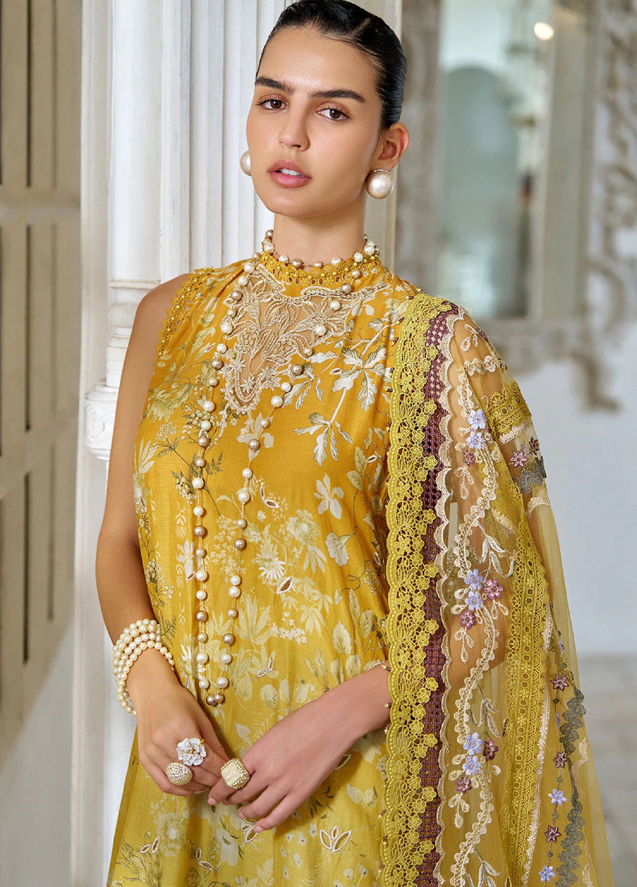 Close-up front view of the woman wearing the embroidered mustard suit with detailed embroidery on the chest and sleeves, and layered pearl necklaces and earrings.