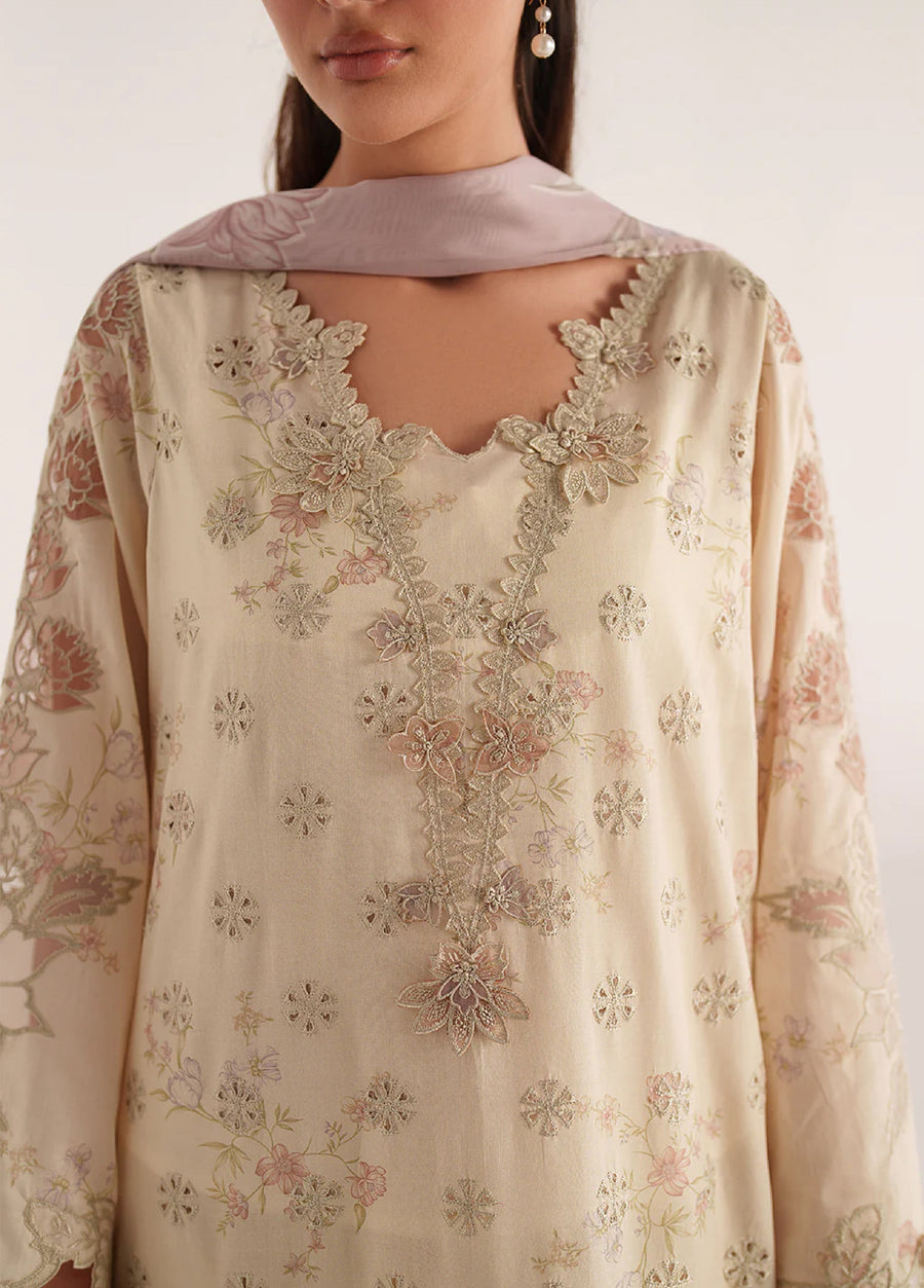 Close-up of the hem of the cream embroidered kameez paired with printed cream trousers and golden sandals