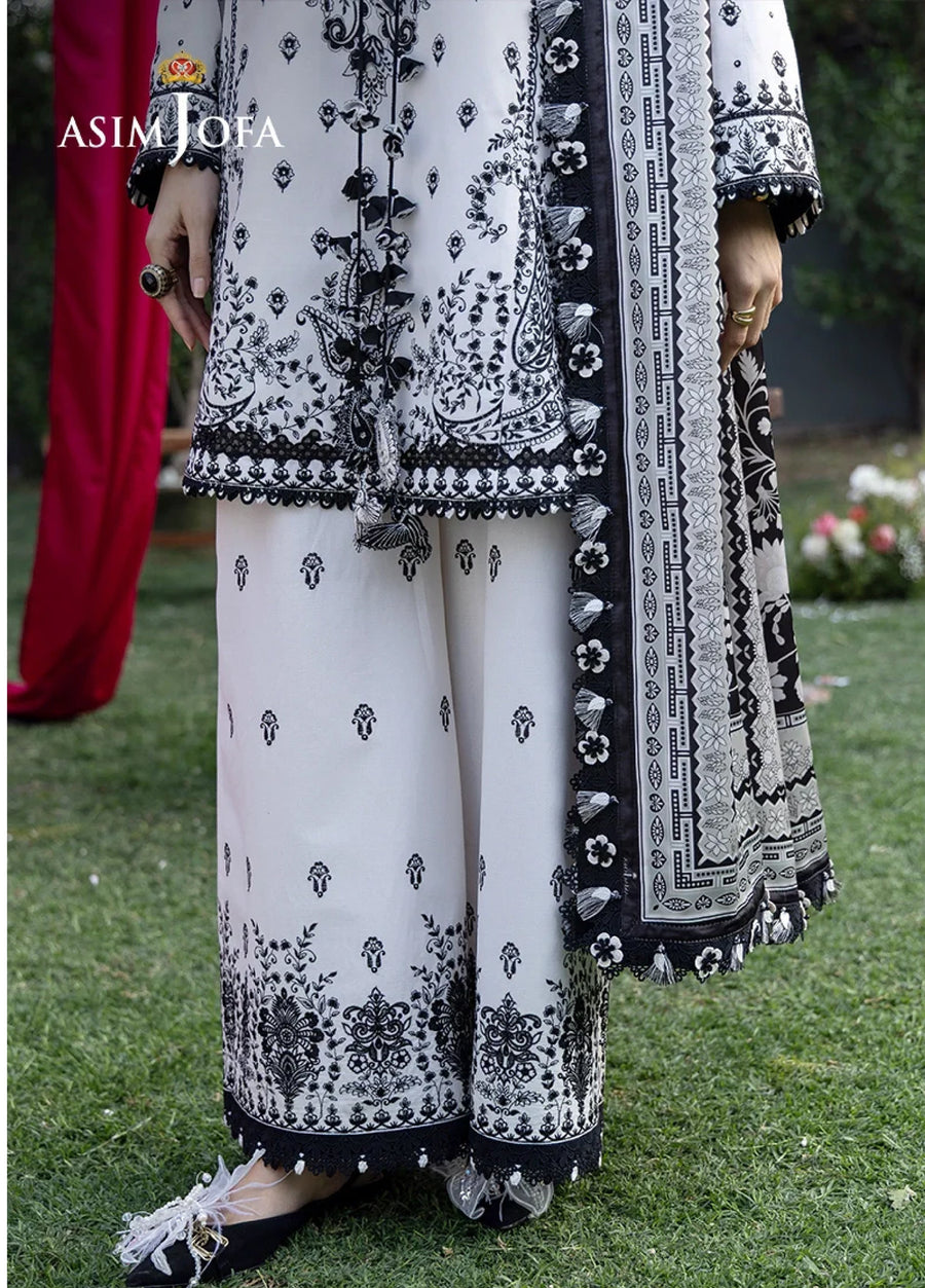 Close-up of wide-leg trousers with black embroidery on white fabric and coordinating black and white embroidered dupatta with tassel edges.