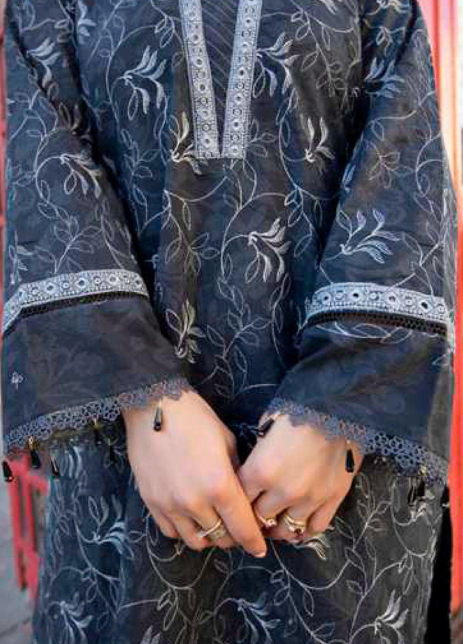 Close-up of embroidered lawn suit sleeves and hands adorned with rings, showcasing lace trim and bead tassels on cuff