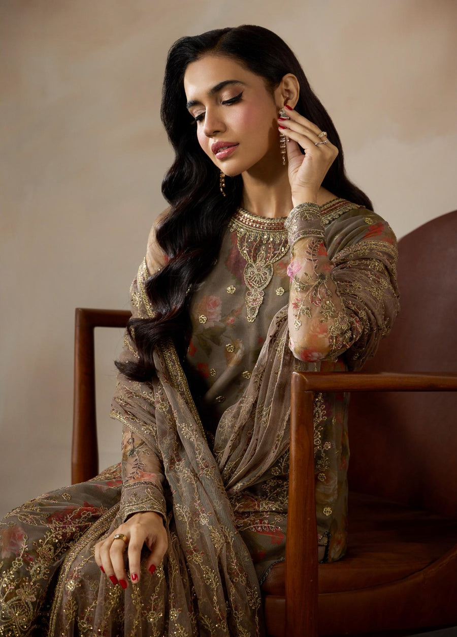 Close-up of model showcasing long black wavy hair, detailed golden embroidery on sleeves, and layered earrings with matching rings