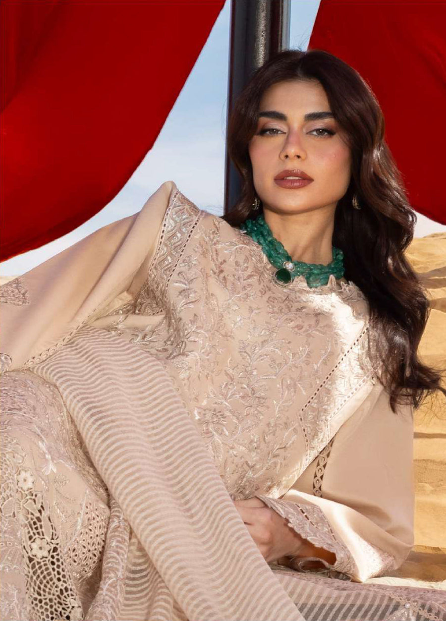 Seated woman posing with beige embroidered lawn suit, highlighting sleeve embroidery, fine fabric texture, and elegant modest styling