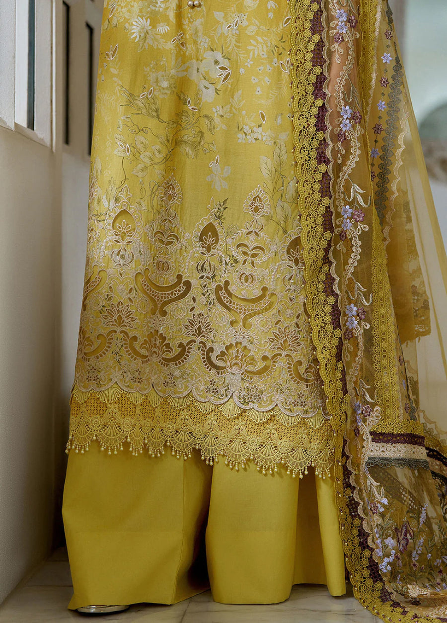 Close-up shot of the lower part of the suit showing complex floral lace embroidery on the shirt’s hem paired with plain mustard yellow wide-leg pants.