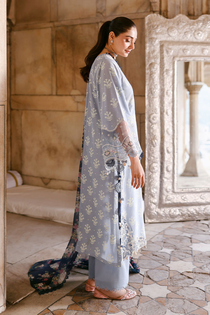 Side profile of woman wearing sky blue embroidered lawn suit with navy printed chiffon dupatta by ornate mirror