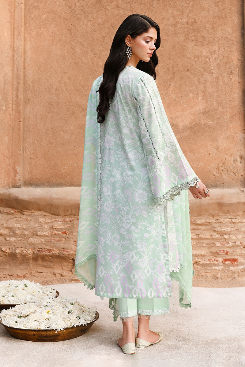 Rear view of woman in sage green three-piece lawn suit displaying floral prints, lace edging on sleeves and hemline, paired with matching trousers and chiffon dupatta