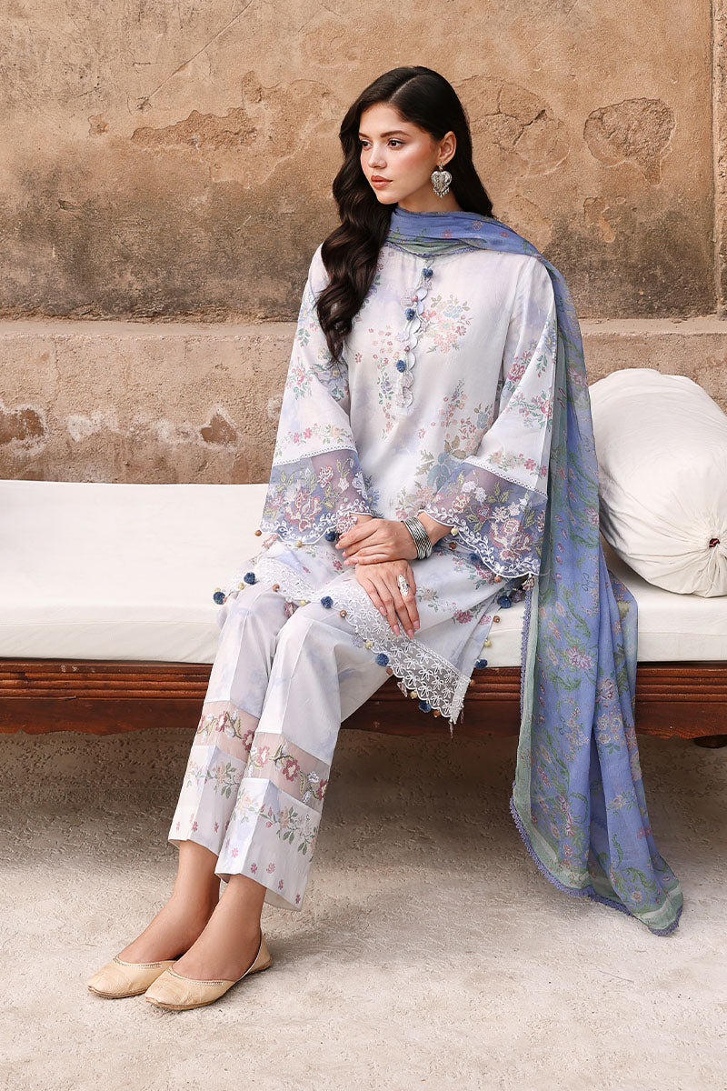 Seated woman wearing Vintage Petal lawn suit in pastel floral print with embroidered sleeves and blue chiffon dupatta draped over shoulder