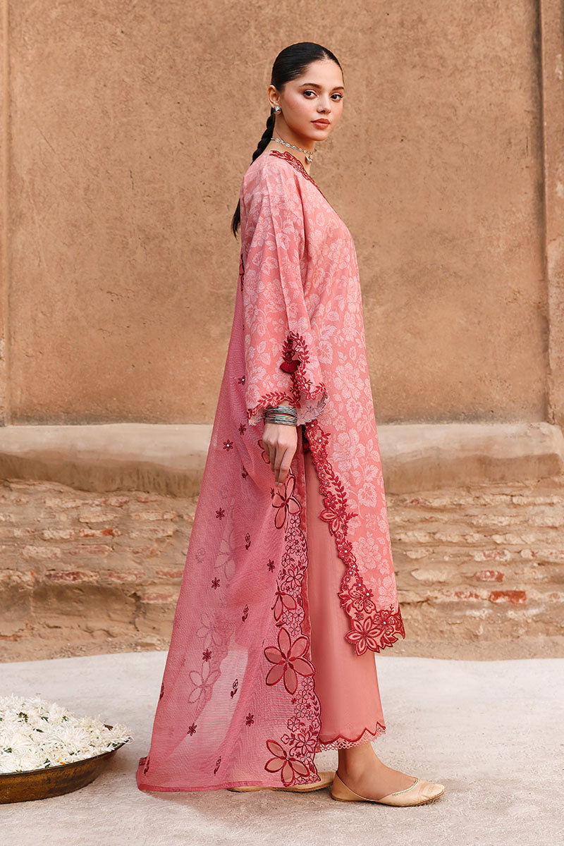 Side view of woman standing in an embroidered lawn suit featuring scalloped edges and matching pants with traditional footwear.