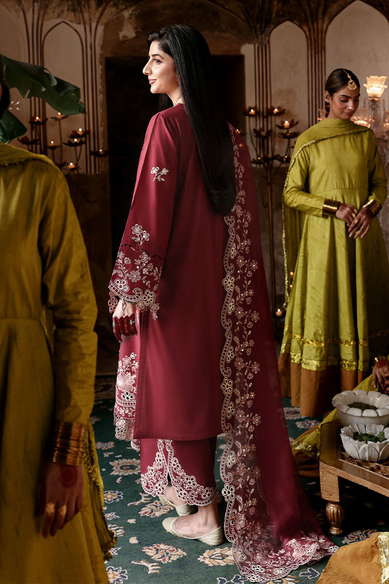 Back view of woman in embroidered crimson lawn suit showcasing embroidery on sleeves and trousers, standing near women in green attire