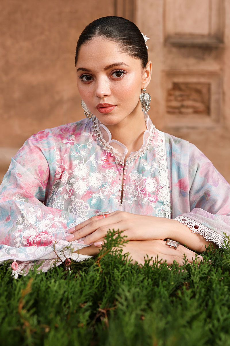 Close-up of woman with pastel floral embroidered lawn suit showing intricate white embroidery and pearl buttons