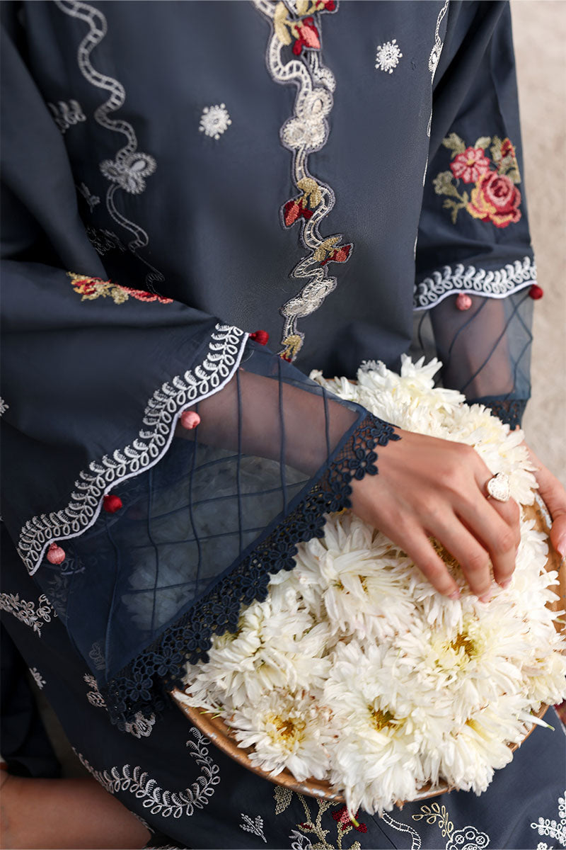 Close-up of sleeve cuff design with mesh detailing, scalloped embroidery, and pom-pom accents on the dark formal suit